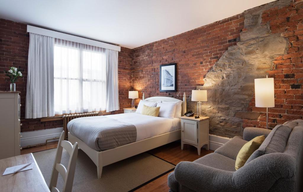 魁北克市Auberge Saint-Pierre的一间卧室设有一张床和砖墙