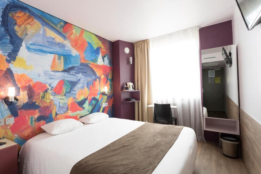 托尔西Brit Hotel Codalysa Marne la Vallée - Torcy的酒店客房设有一张床,墙上挂有绘画作品