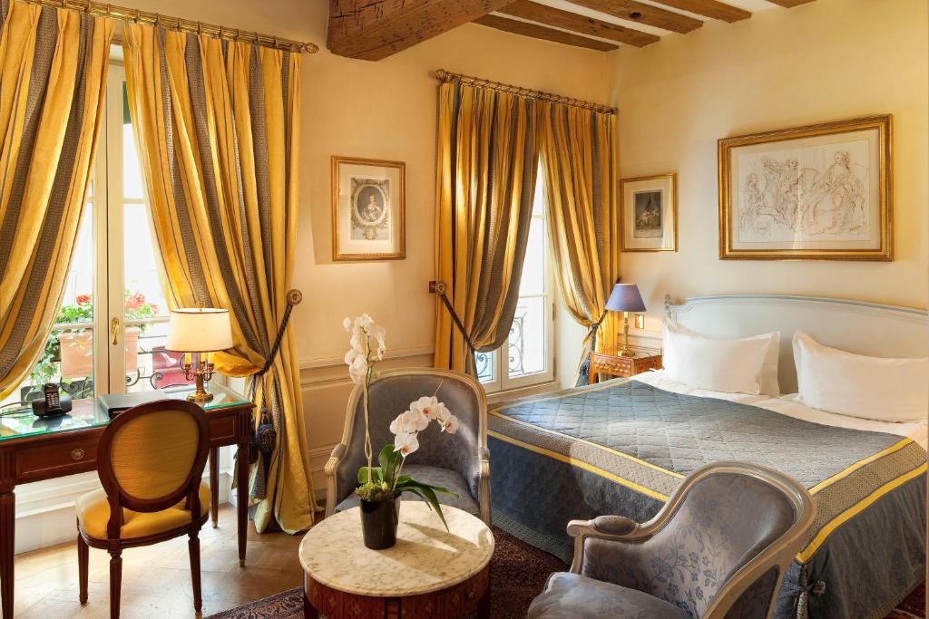 巴黎卢森堡公园酒店的卧室配有一张床和一张桌子及椅子