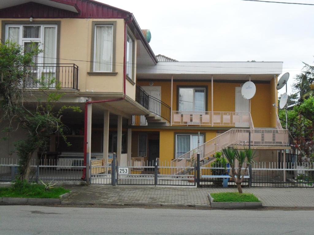 科布列季Guest House Nika的黄色的房子,上面有门廊和楼梯
