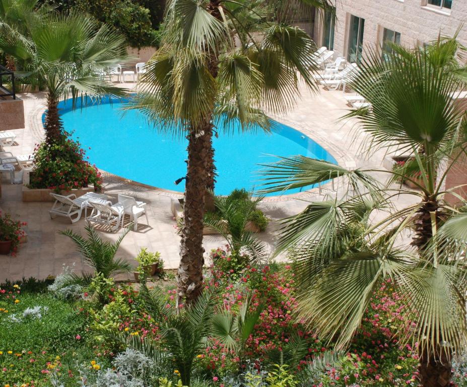 瓦迪穆萨佩特拉宫殿酒店 的一座种植了棕榈树和植物的大型游泳池