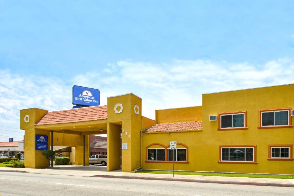 阿苏萨美洲最佳价值旅馆 - 阿祖瑟/帕萨迪纳的黄色的建筑,上面有标志