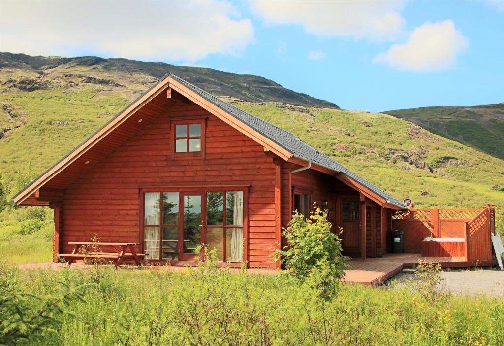 雷克霍特Geysir - Modern Log Cabin的小木屋,后面是一座草木山丘