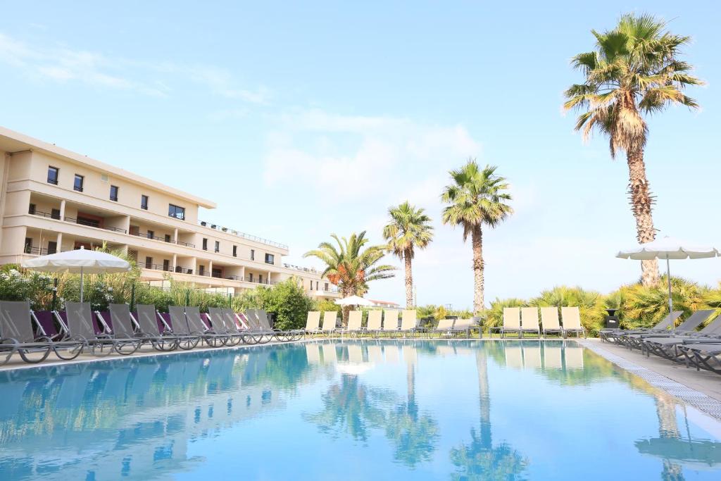马赛金色郁金香马西利亚别墅酒店的一座带椅子和棕榈树的度假村游泳池