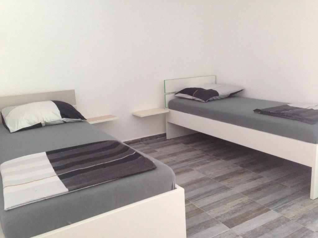 特罗吉尔客房休闲海滩旅馆的配有白色墙壁和木地板的客房内的两张床