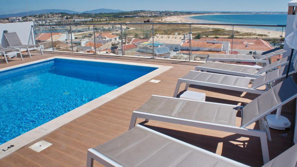 拉戈斯Topcity Hostel & Suites的一个带椅子的游泳池,享有海滩美景