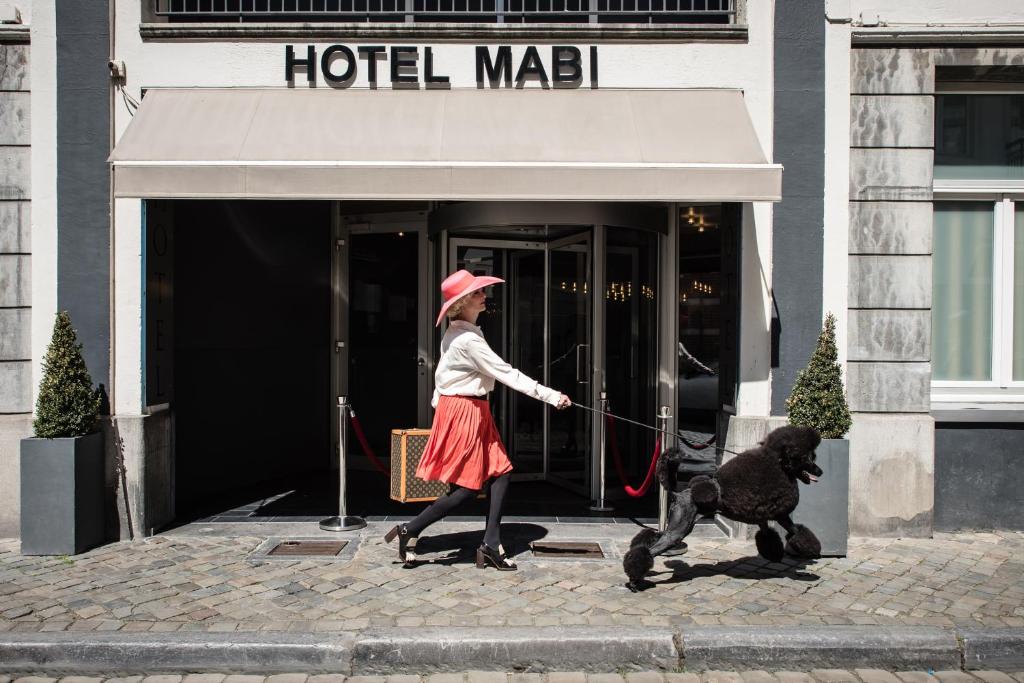 马斯特里赫特Mabi City Centre Hotel的一只用皮带带走狗的女人