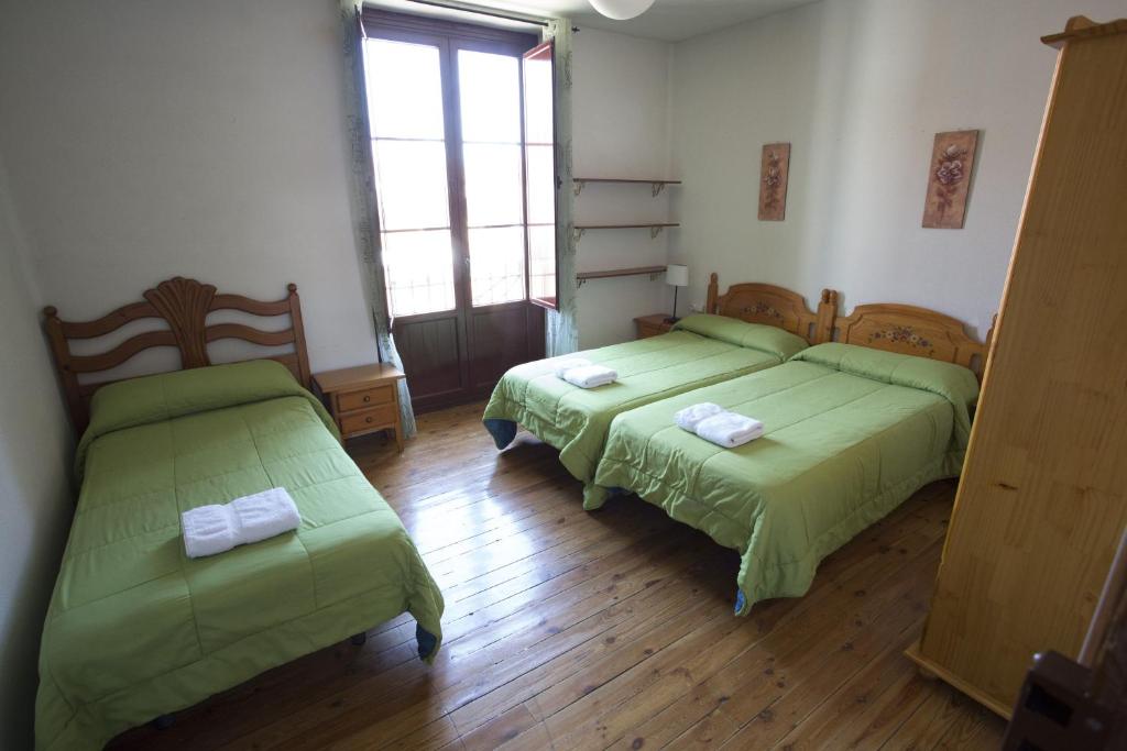 莱昂桑多瓦尔旅馆的配有绿床单的客房内的两张床