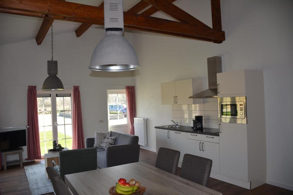 黑泽De Rulse Hoeve的一间厨房和客厅,客厅内配有木桌。