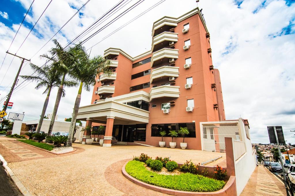 马里利亚马里利亚JR酒店的前面有棕榈树的粉红色建筑