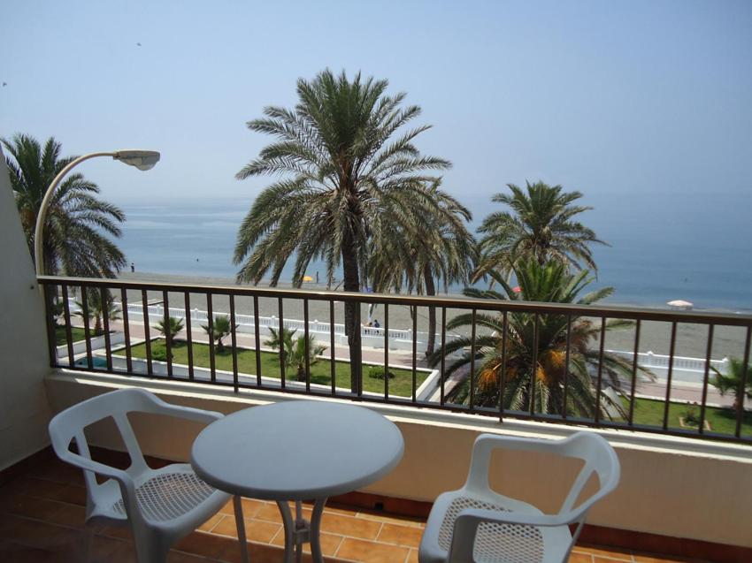 拉拉维塔Hotel las Conchas的阳台配有桌椅,享有海滩美景。
