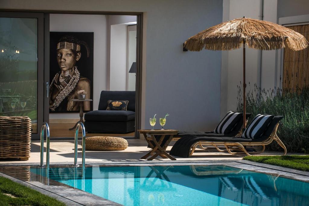 玛利亚玛利亚太阳村套房精品公寓式酒店的房屋旁的游泳池配有椅子和遮阳伞