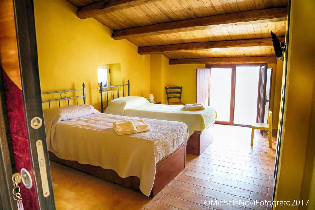 圣尼科拉阿尔切拉La Casa di Ivana的黄色墙壁客房的两张床