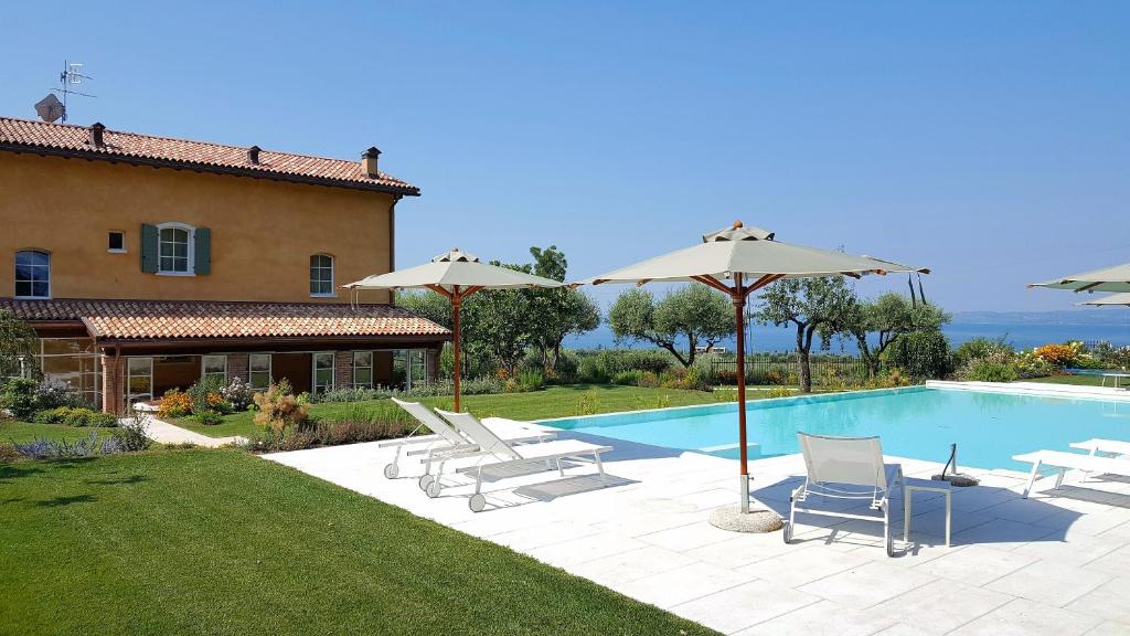 巴多利诺Ca Muretta Relais的房屋旁的游泳池配有椅子和遮阳伞