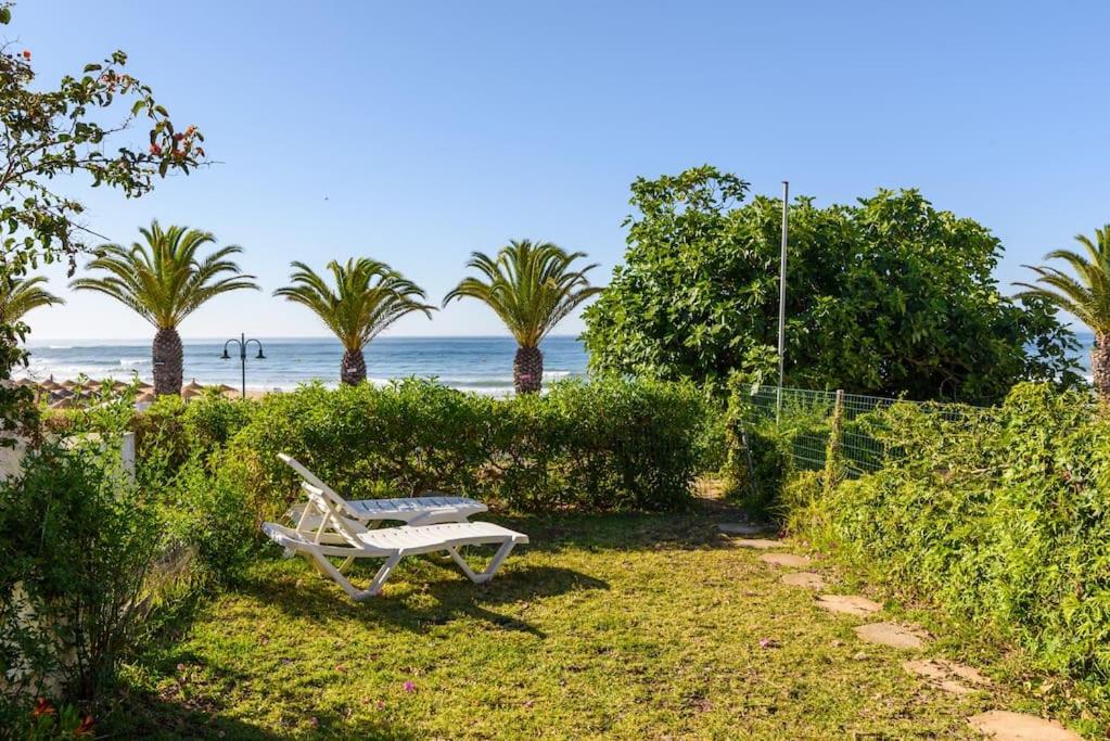 卢斯Casa Sol e Praia的坐在海滩附近的草地上的白色长凳