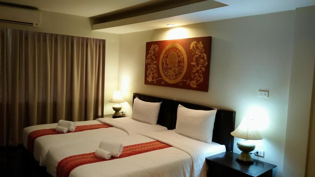 Sawankhalok萨旺卡布里精品酒店的酒店客房设有两张床和两盏灯。