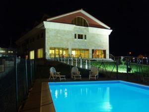 洛雷多Hotel Estrella del Alemar的夜间在房子前面的游泳池