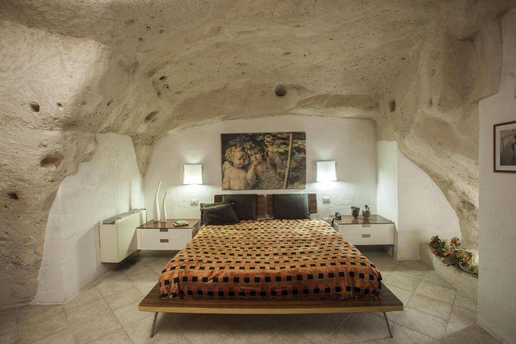 马泰拉圣皮埃特罗巴里萨诺酒店的卧室配有一张石墙内的大床