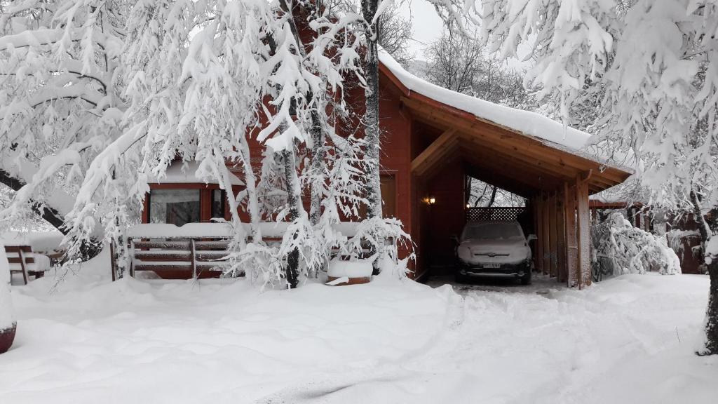 拉斯特朗卡斯Cabañas Tronco Mayen的小屋前面有一辆汽车停放,有雪盖