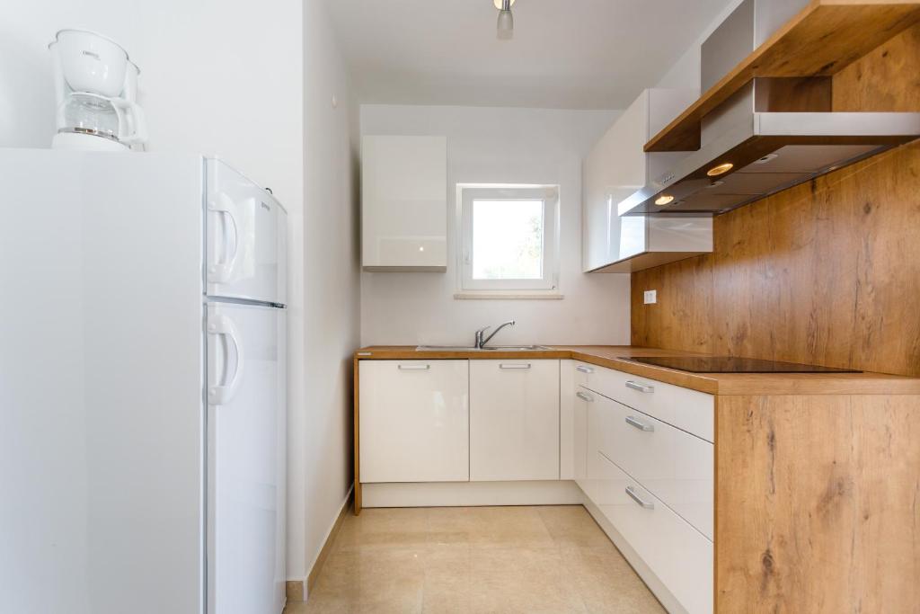 克尔克Apartman Maslina的厨房配有白色橱柜和白色冰箱。