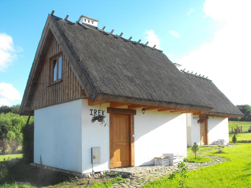 WerbliniaDomki przy lesie的一座白色的小建筑,拥有茅草屋顶