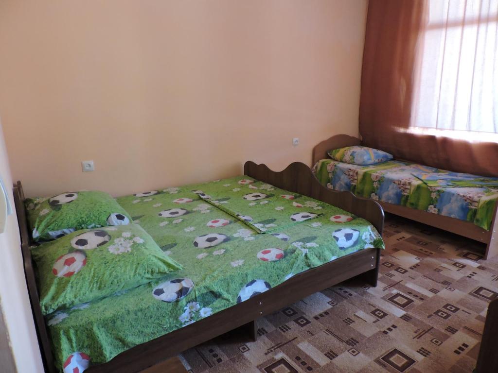 新阿丰Guesthouse U Moti的一间卧室配有两张床,配有带牛的绿色被子