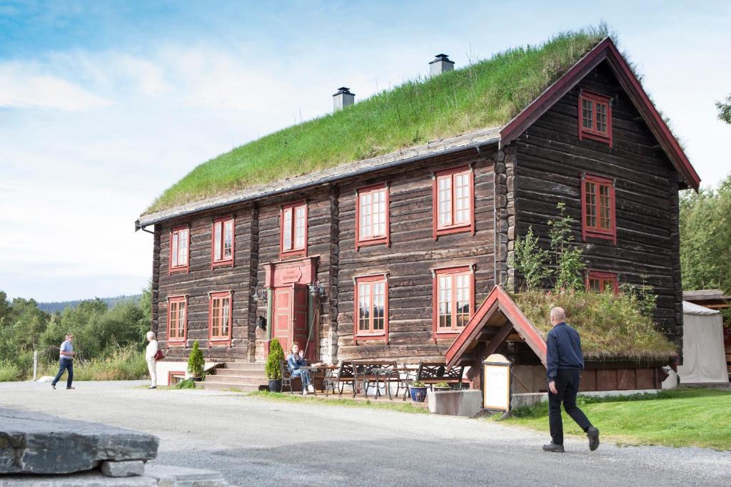 BerkåkBerkåk Gjestegård的人走在有草屋顶的建筑前