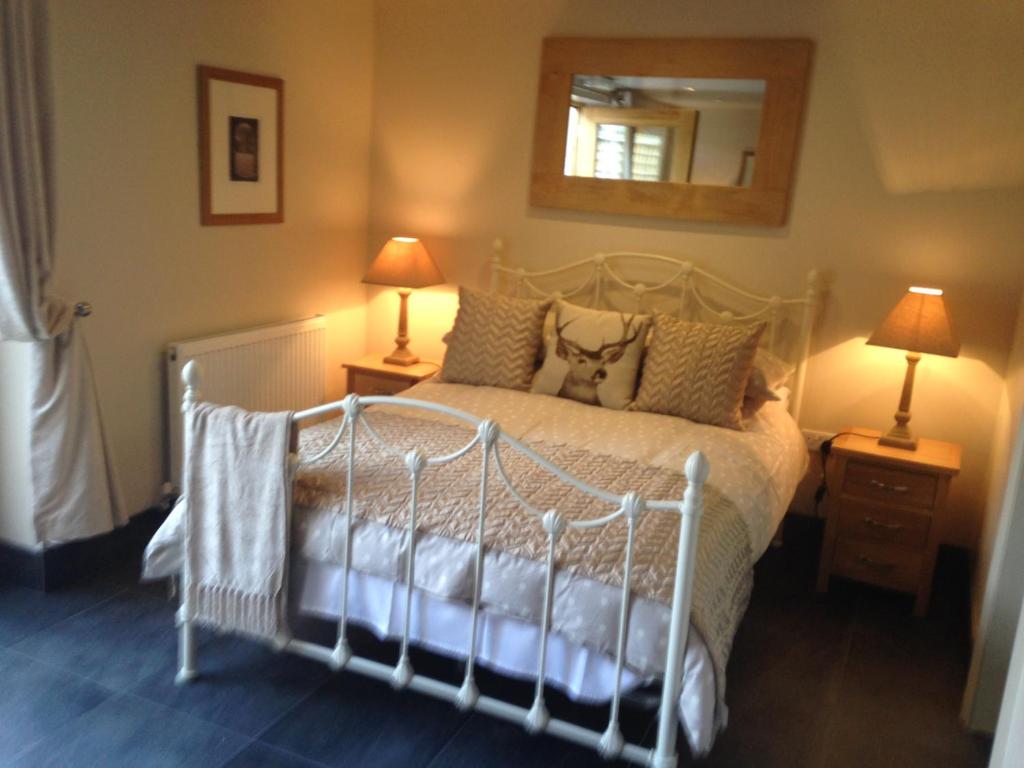 勒德洛The Queens的卧室配有一张带两盏灯和镜子的白色床。