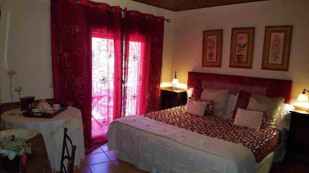 拉斯卡弗里亚钟楼旅馆的一间卧室配有一张带红色窗帘的床和一张桌子