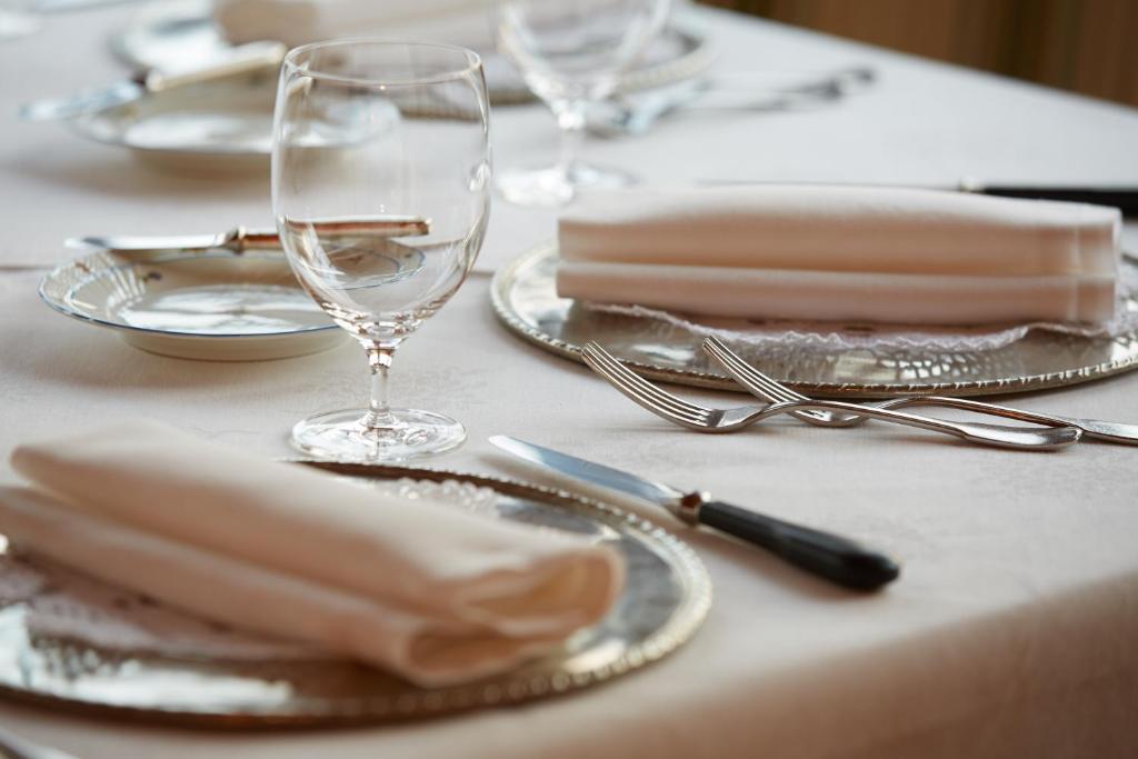 丰多Hotel Alle Ciaspole的一张桌子,上面有盘子和玻璃杯,还有银器