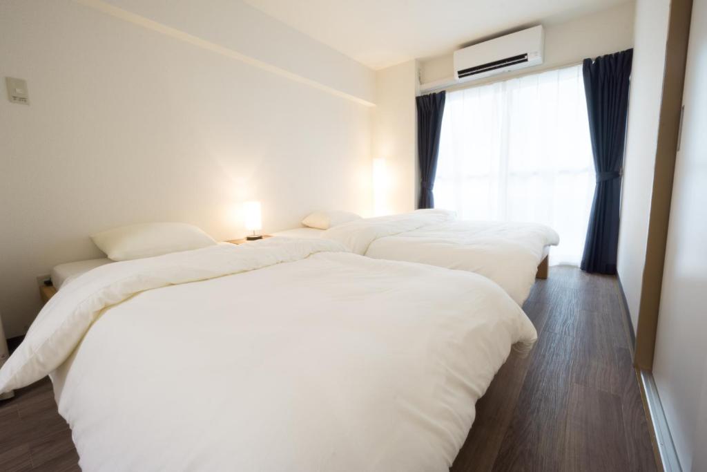 东京东京戈恩公寓式酒店的带窗户的客房内的2张白色床
