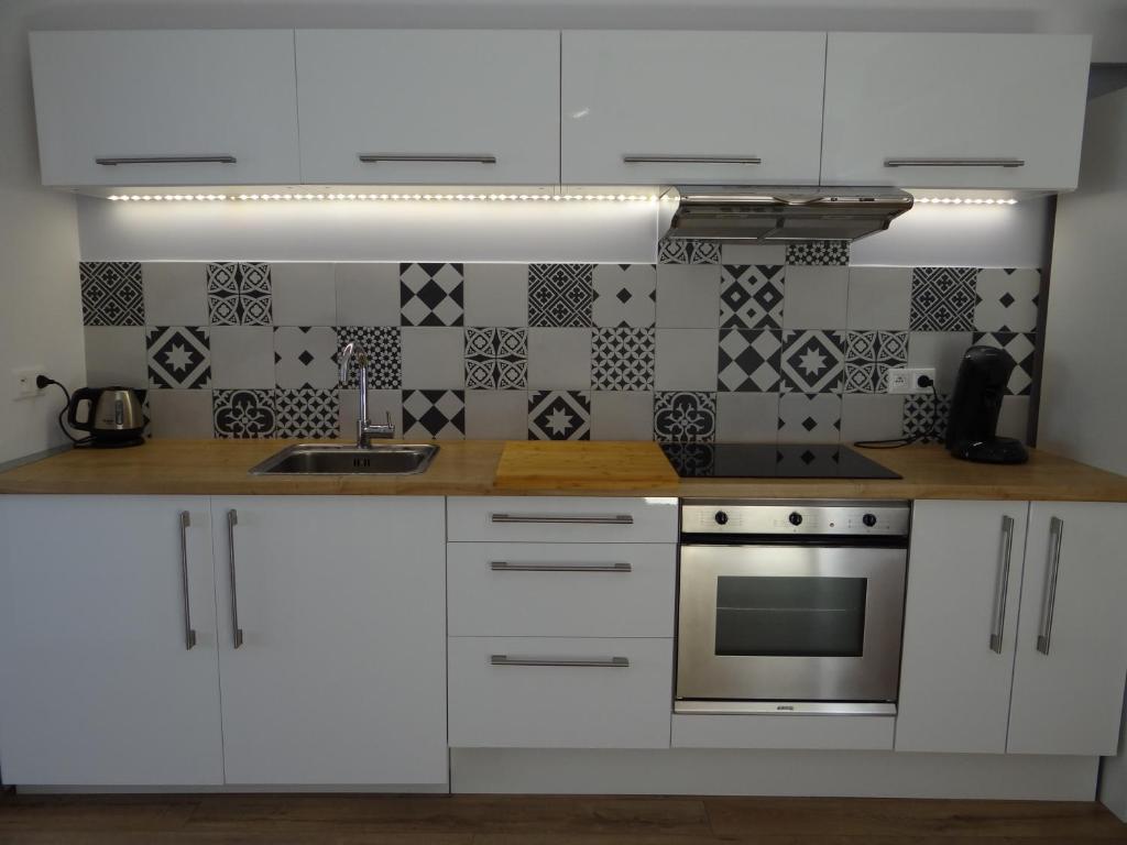 马诺斯克科洛娜公寓的厨房配有白色橱柜和炉灶。