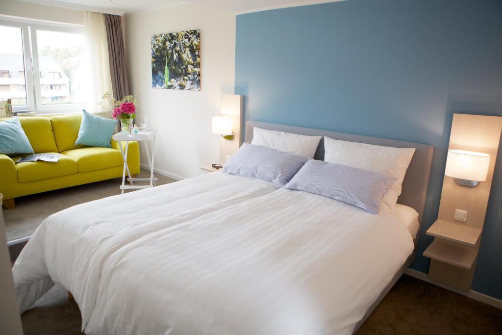 比苏姆Hotel Jess am Meer的卧室配有一张白色大床和一张黄色沙发。