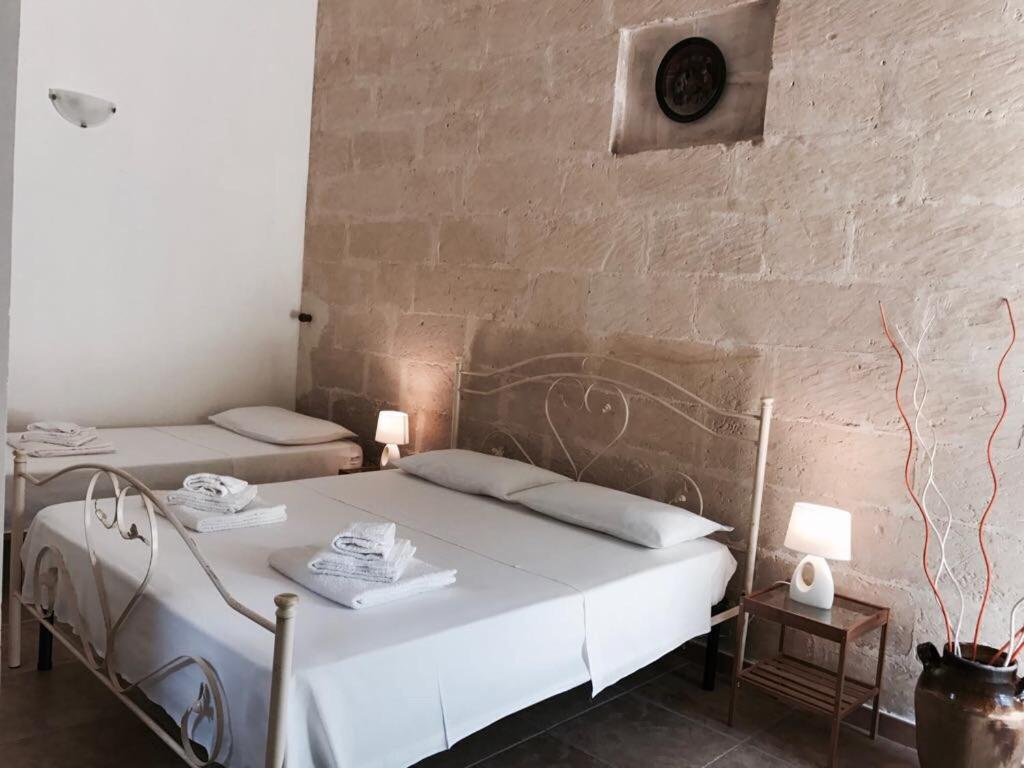 圣切萨廖迪莱切Tenuta "Li Santi"的一间卧室设有两张床和砖墙