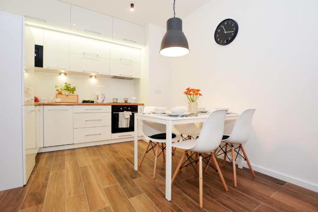 尤斯托尼莫斯基Apartament 27 Dwie Sosny的厨房配有白色橱柜和白色的桌椅