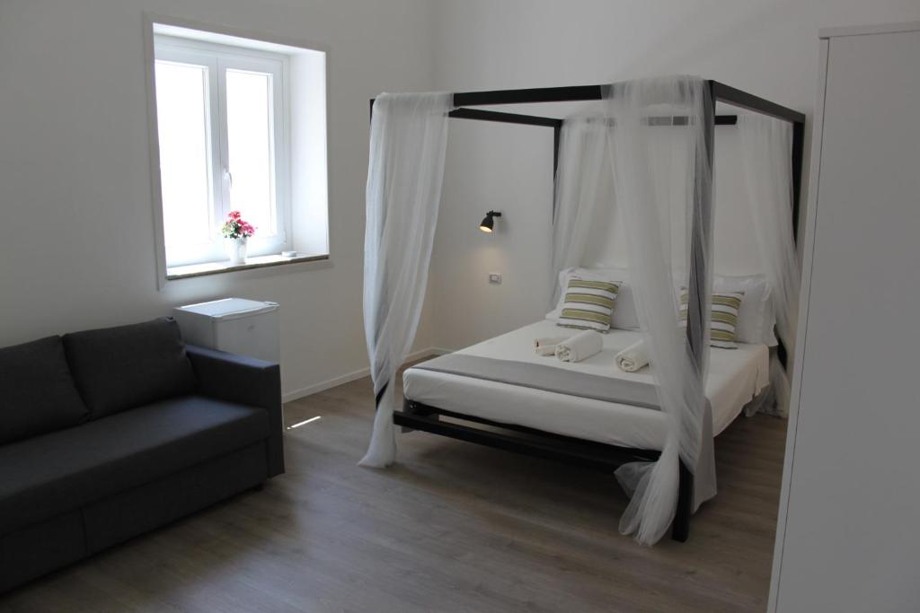 锡拉库扎Dimora di Artemide的一间卧室配有天蓬床和沙发