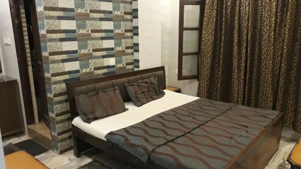 德拉敦Hotel Grand的卧室配有一张床铺,位于带墙壁的房间