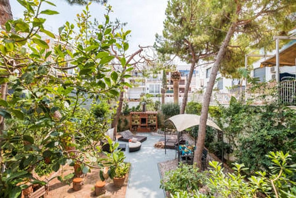 锡切斯3 bedroom Apartment with private garden on top location Sitges centre beach的室外庭院设有树木和椅子以及遮阳伞。