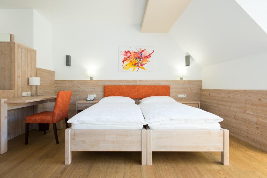 ErnsthofenHotel Vösenhuber的一间卧室配有一张床、一张桌子和一把椅子