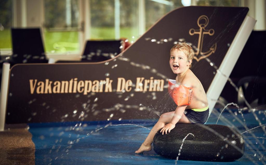 德科克斯多普克瑞姆特克塞尔度假公园的坐在水面冲浪板上的男孩
