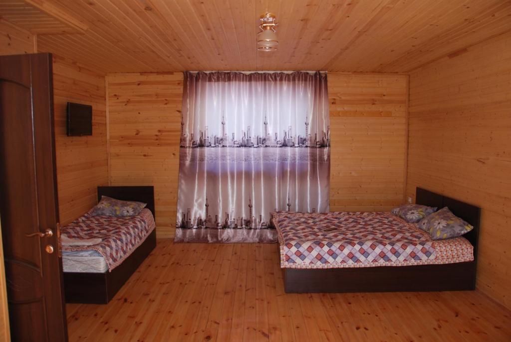 乔尔蓬阿塔Guest house Ozernaya的一间卧室设有两张床,窗户配有窗帘