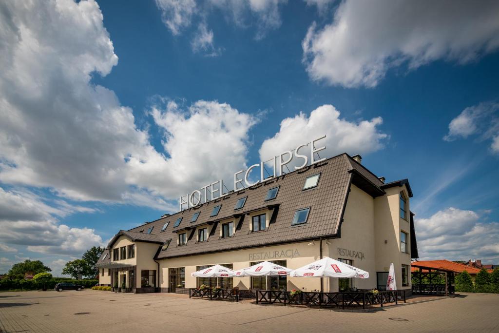 Domasław伊柯丽斯酒店的前面设有桌子和遮阳伞的酒店