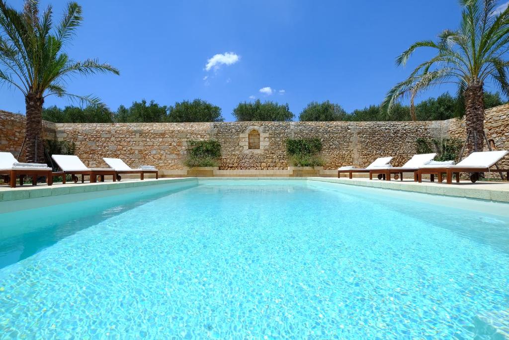 佩斯科勒海滨Relais Masseria Sant'Antonio的一个带椅子的游泳池,砖墙