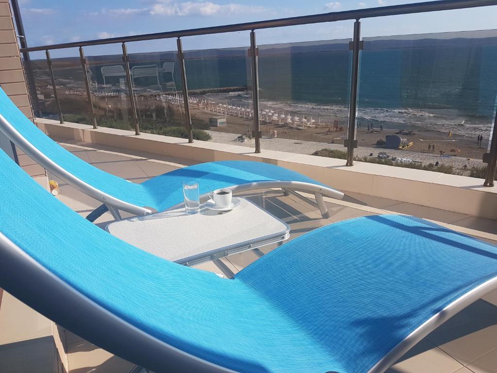 帕莫瑞Apart Hotel Iglika的阳台配有蓝色椅子和桌子,享有海景。