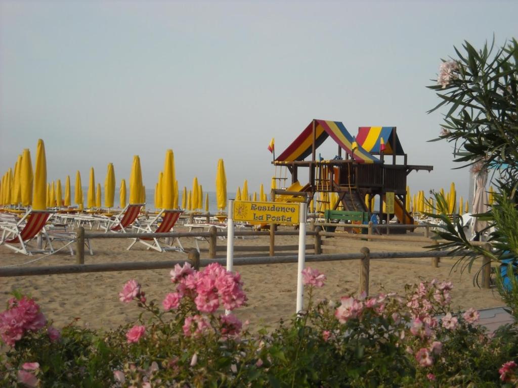 利多迪耶索罗B&C Apartments LA POSTA Home的海滩上设有游乐场、椅子和遮阳伞