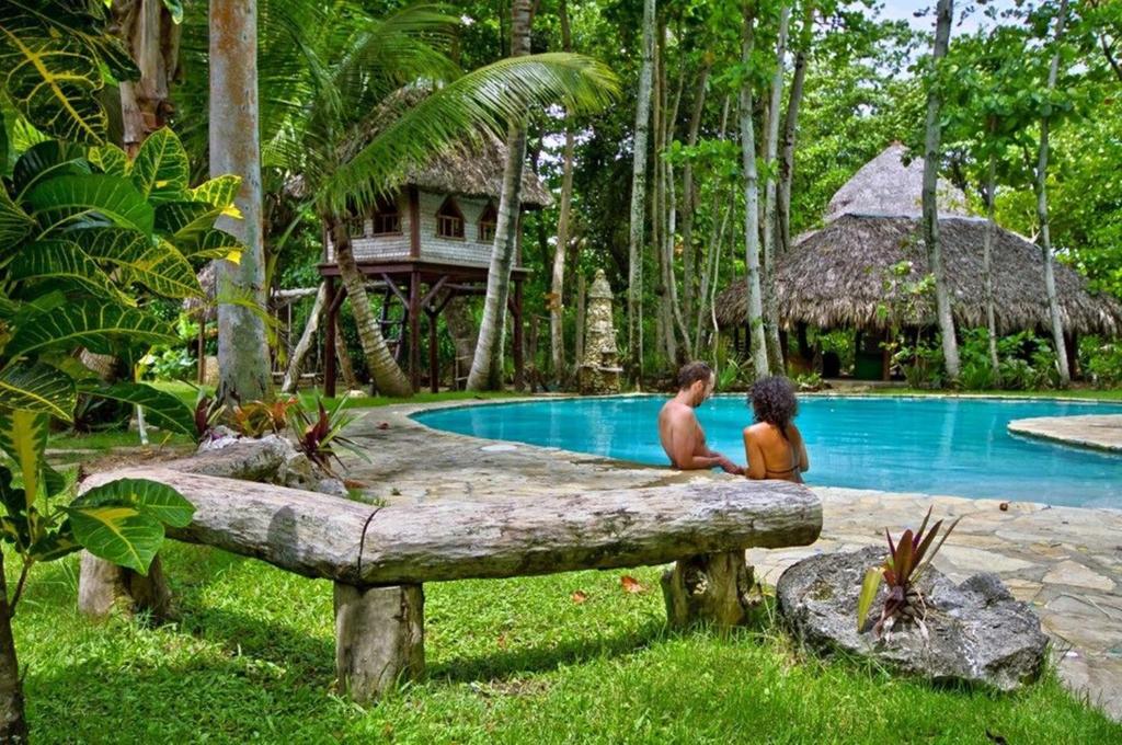 喀巴里特Natura Cabana Boutique Hotel & SPA by Mint的坐在游泳池旁的木柴上的男人和男孩