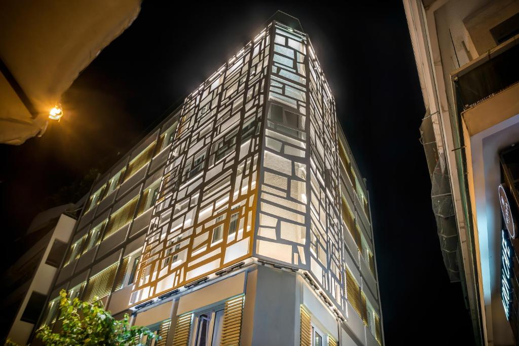 雅典雅典AD豪华套房酒店的一座晚上有灯的建筑