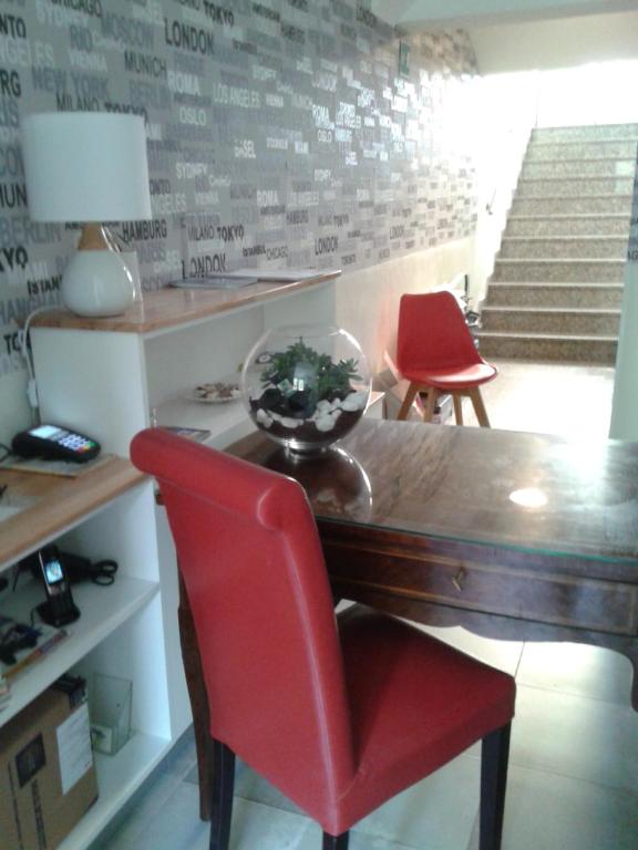 米兰马耳他酒店的一间带桌子和两张红色椅子的用餐室