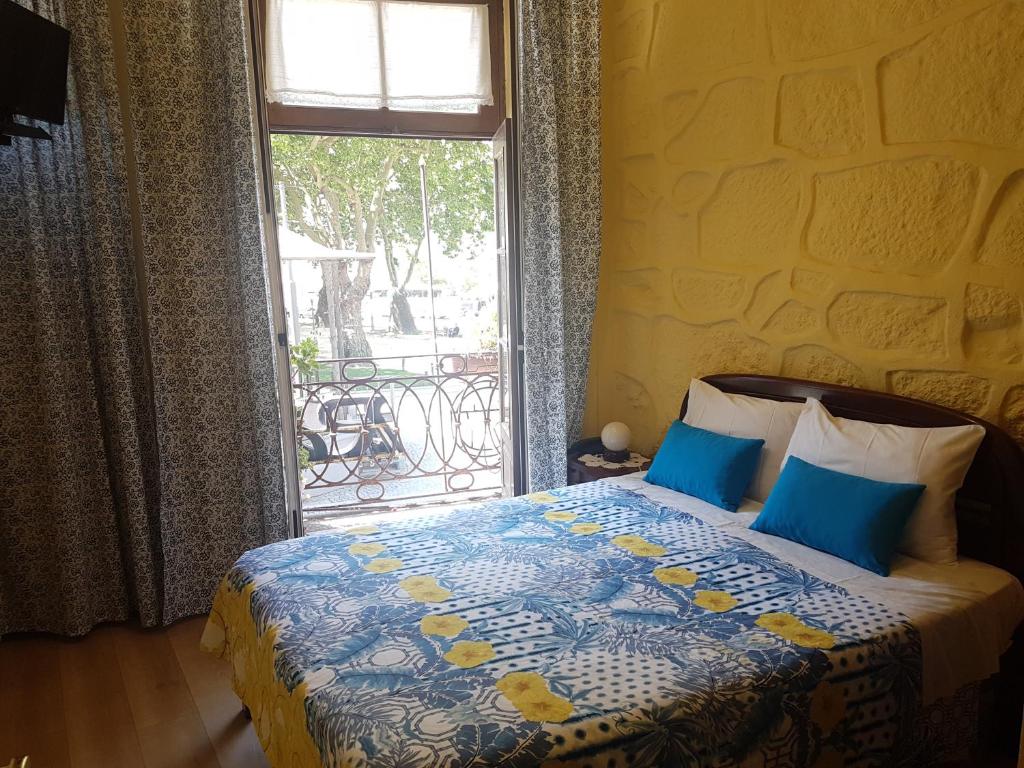 波尔图Caldeira Guest House的一间卧室配有一张带蓝色枕头的床和一扇窗户。