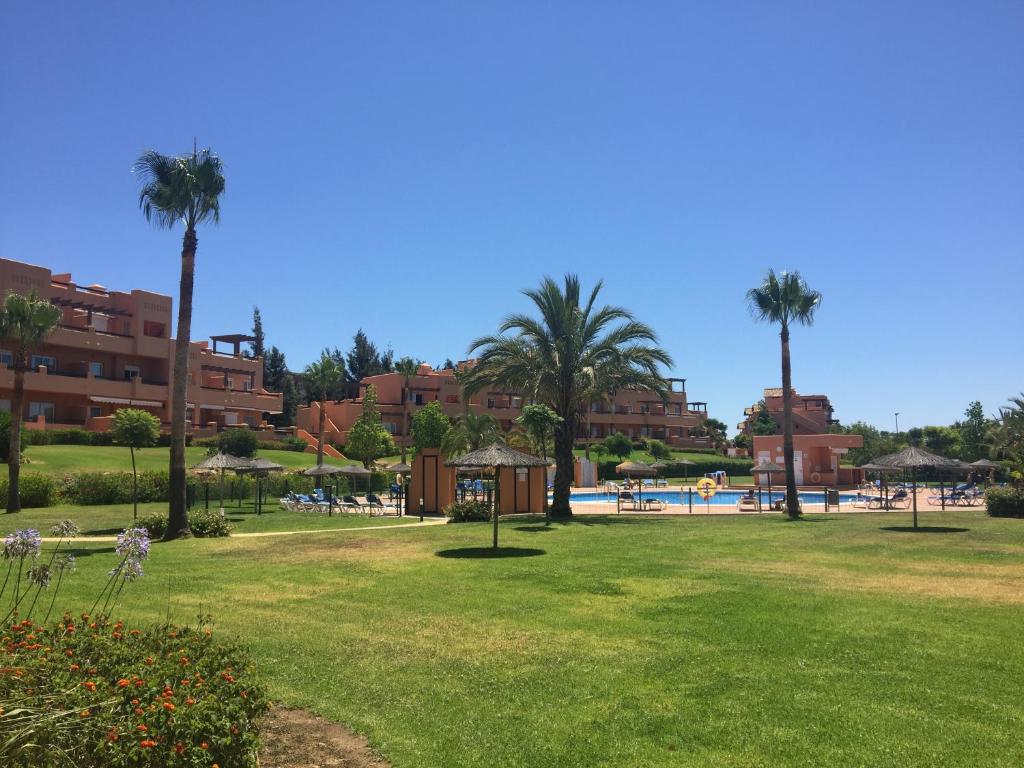卡萨雷斯Madre Mia Apartment的一座公园,公园里设有游泳池,棕榈树和建筑